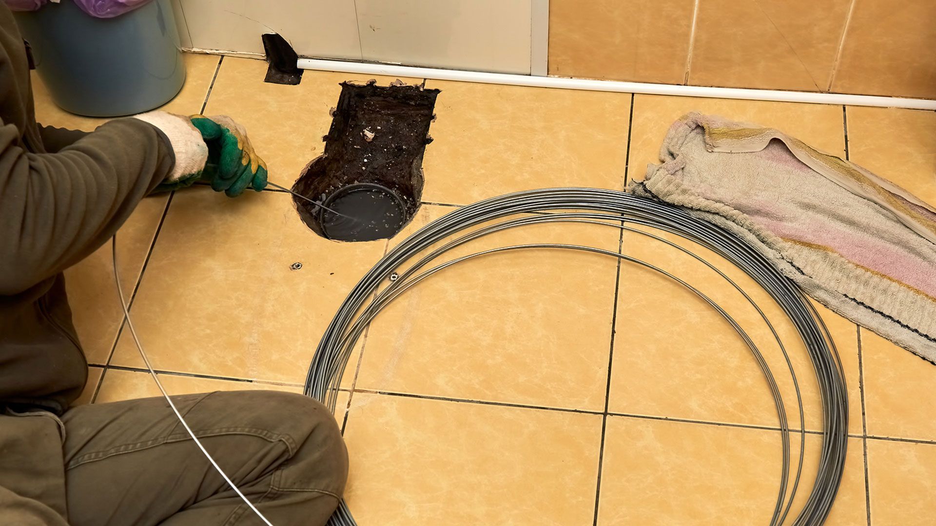 A man is kneeling on the floor next to a hose.