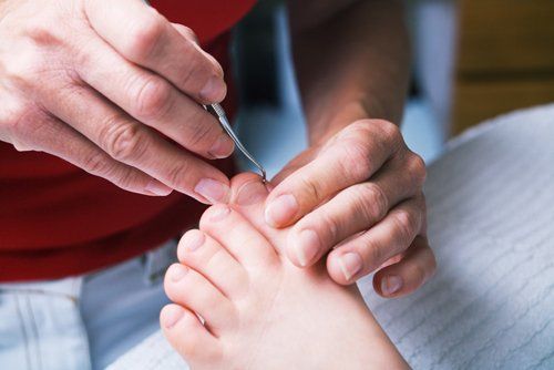 A woman performing foot care on a girl's foot (close up)