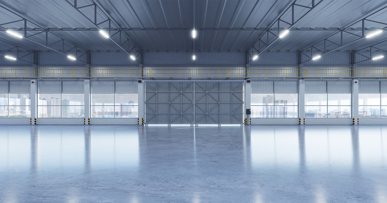 Empty industrial warehouse with polished concrete floor, large windows, and overhead lights