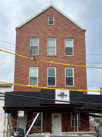 Three-story brick building with black awning and yellow utility lines across the front