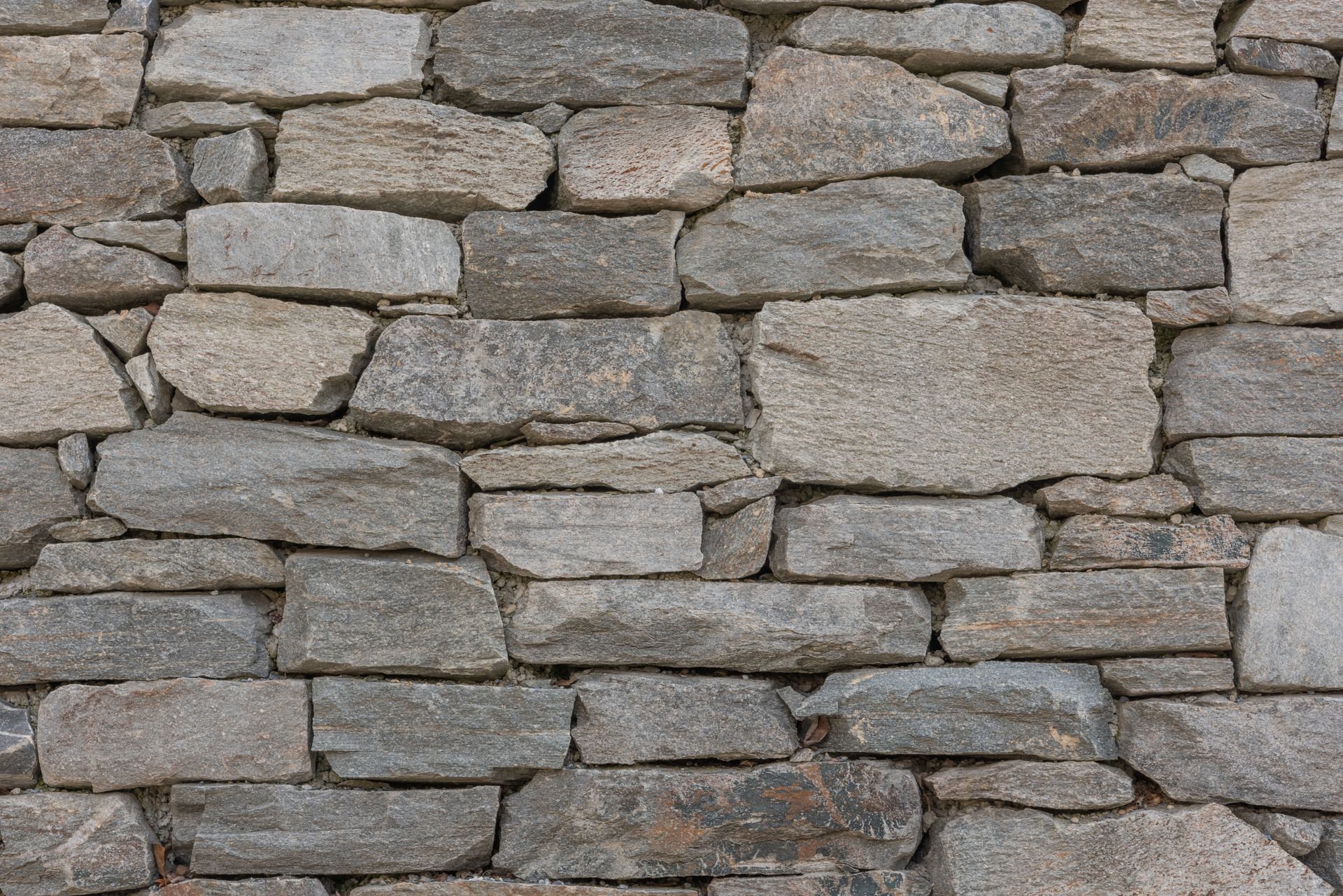 Close-up of a gray stone wall made of uneven stacked rocks