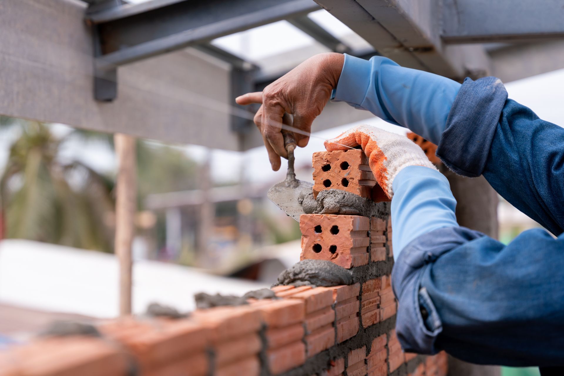 Two workers laying red bricks on a wall at a construction site