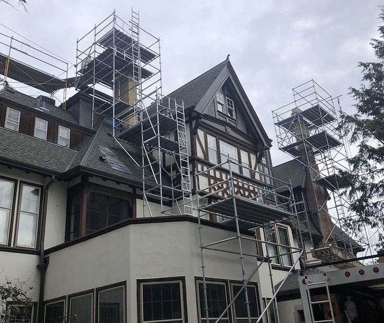 Old Tudor-style building with scaffolding on the exterior under overcast skies