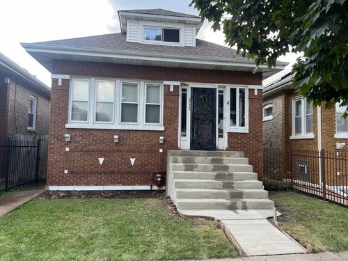 Brick house with a front porch, arched entry, and manicured lawn under trees.