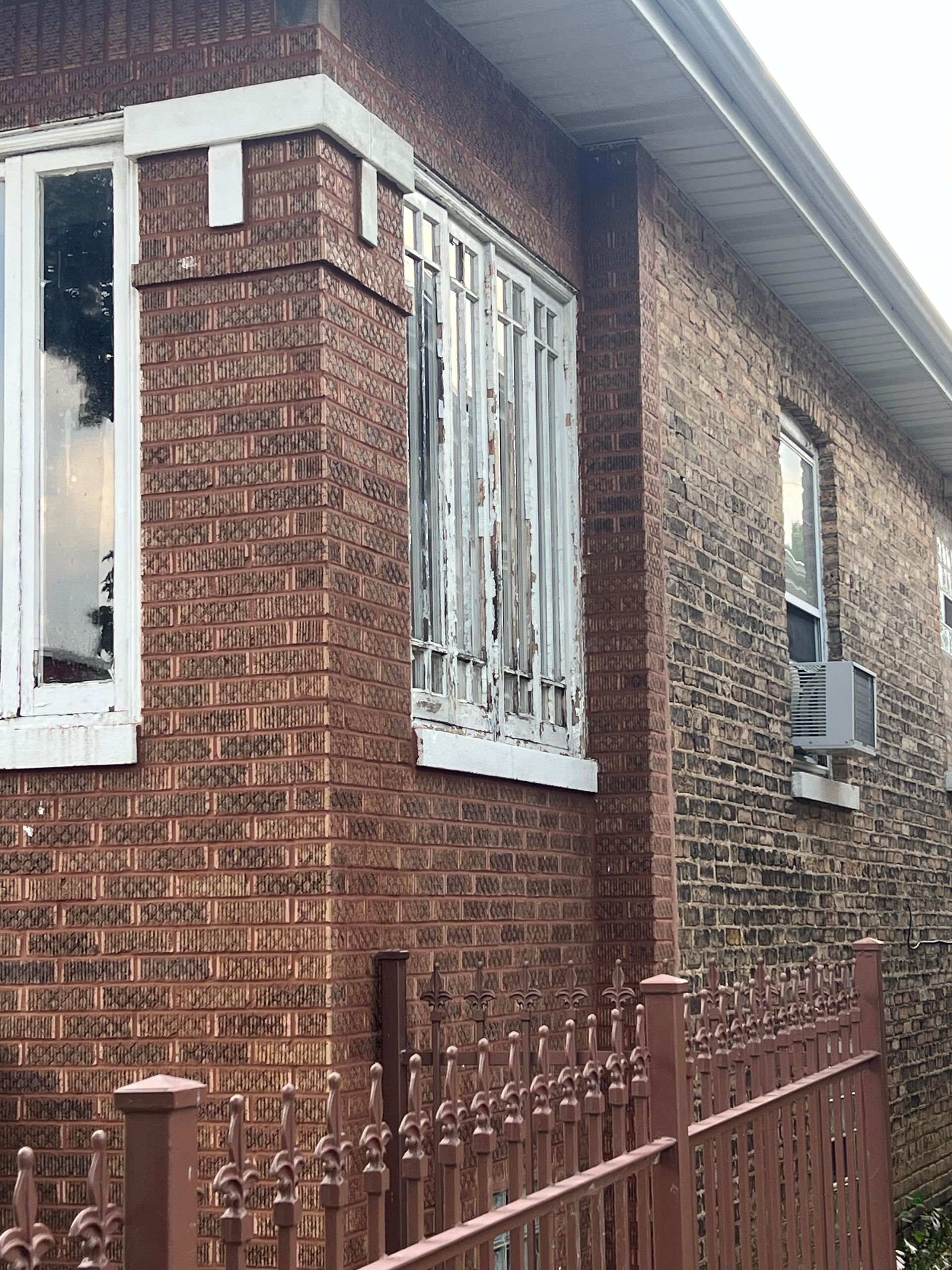 Red brick house facade with white-trimmed windows and a red front door.