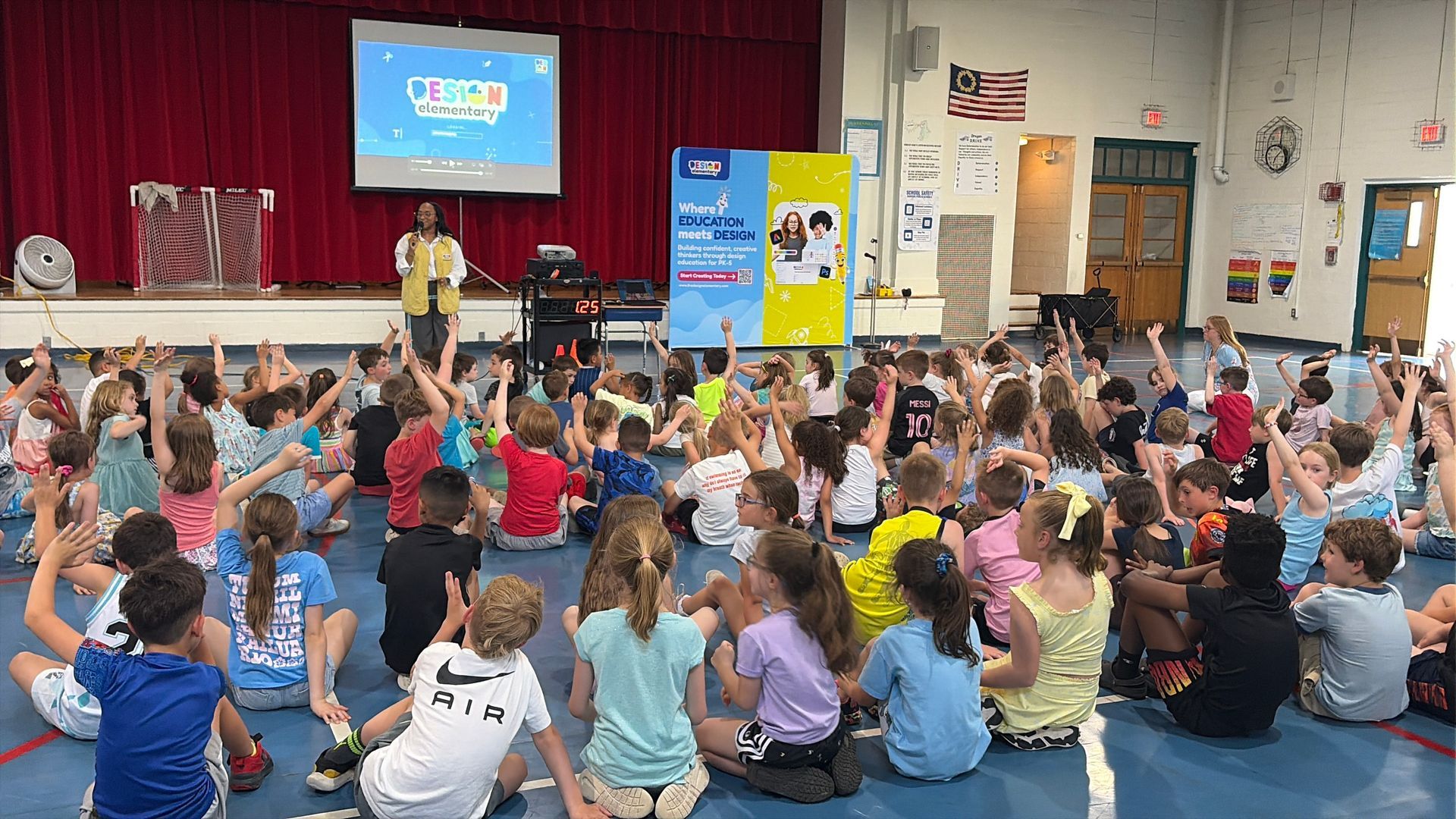 Girl with arms raised in excitement at a laptop. Yellow top, headphones, desk setting.