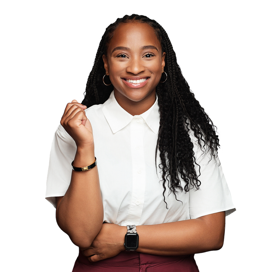 Woman with long black braids smiles, arms crossed, wearing a white button-down shirt.
