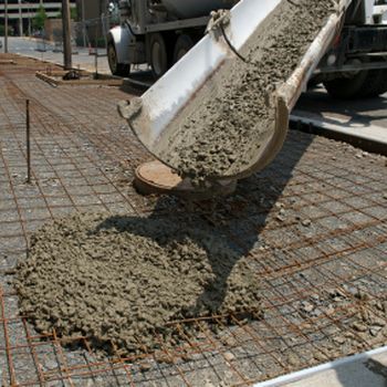 Concrete pouring from a truck chute onto rebar at a construction site