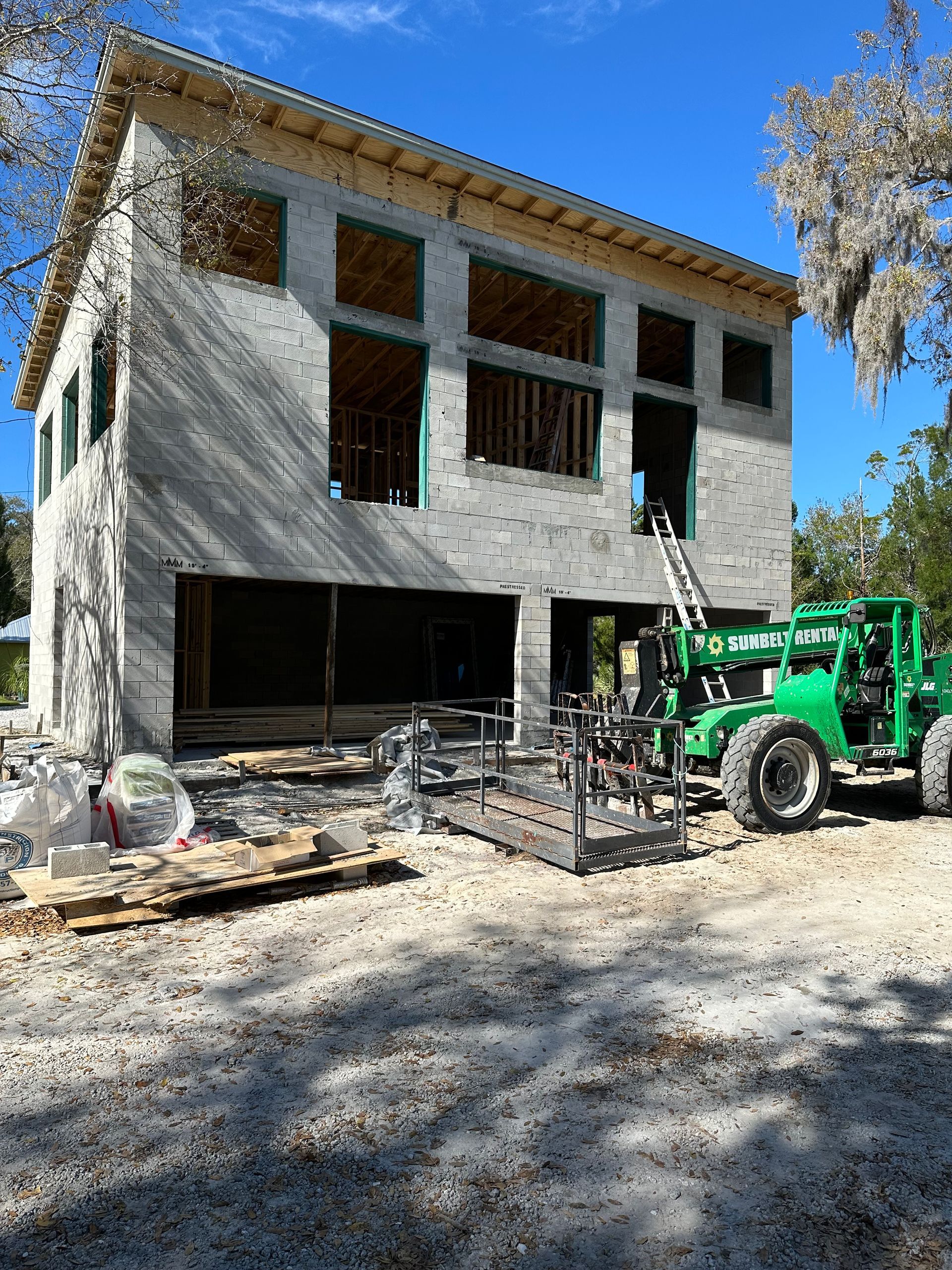 Partially built two-story house with a green tractor and construction materials in front
