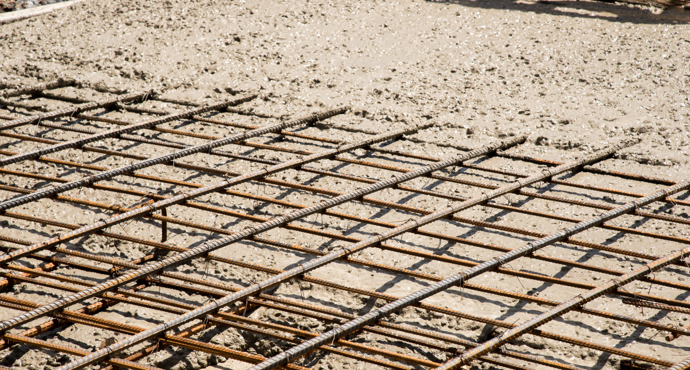 Rebar grid embedded in wet concrete, forming a reinforcing mesh on a construction site