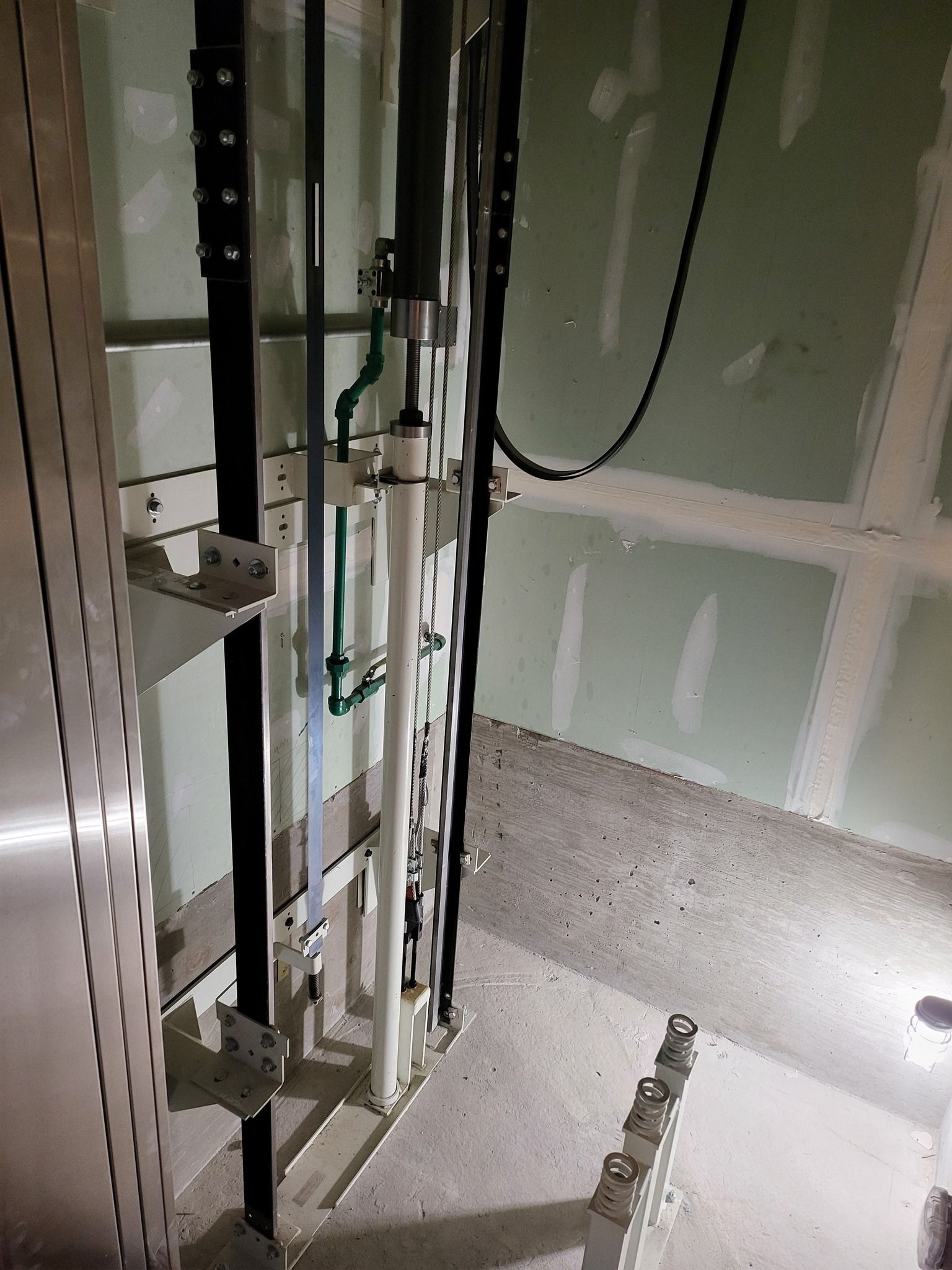 Partially finished room with exposed wall framing, drywall seams, and plumbing pipes during construction