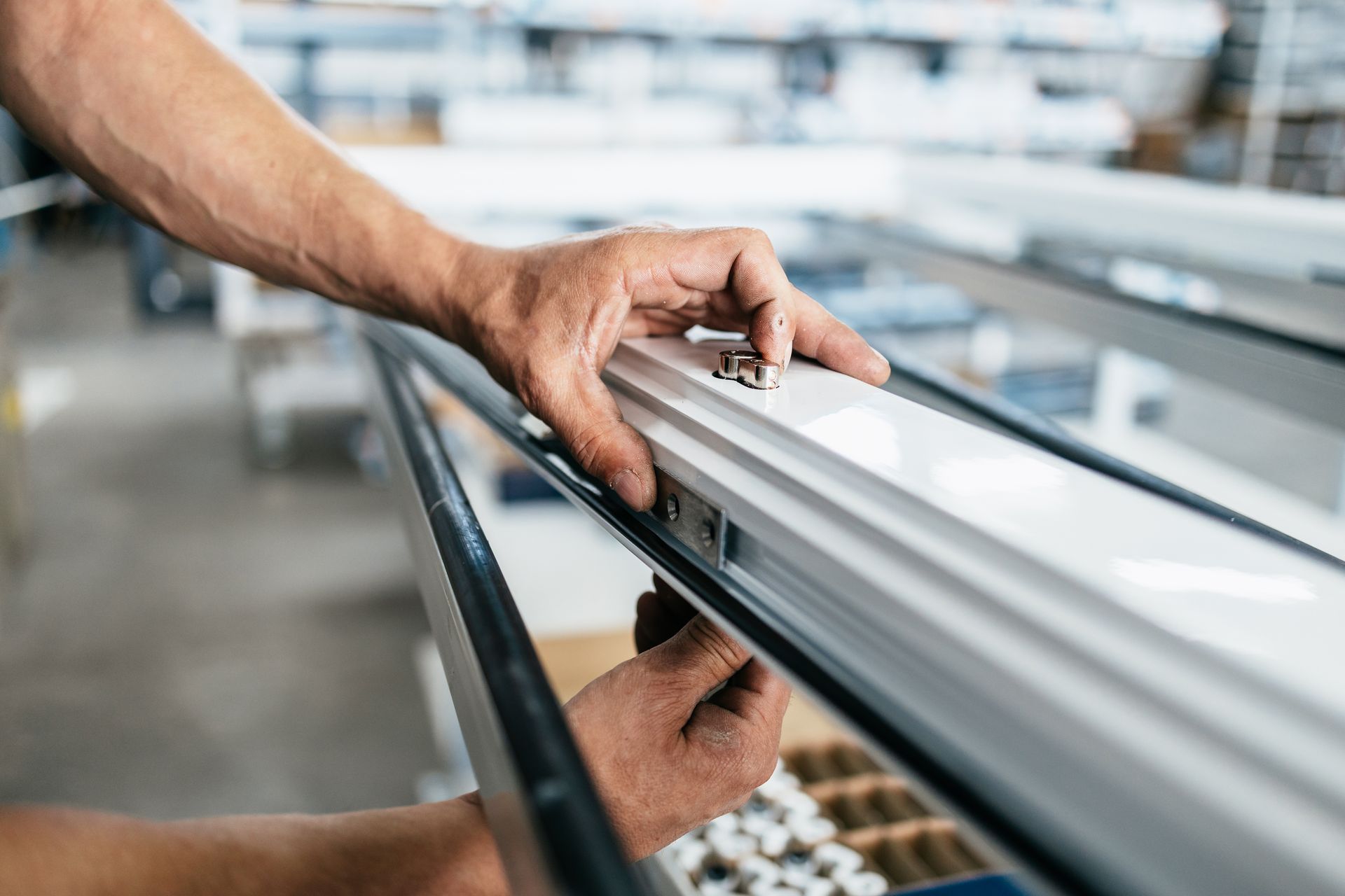 Hand adjusting a metal frame on an industrial conveyor line