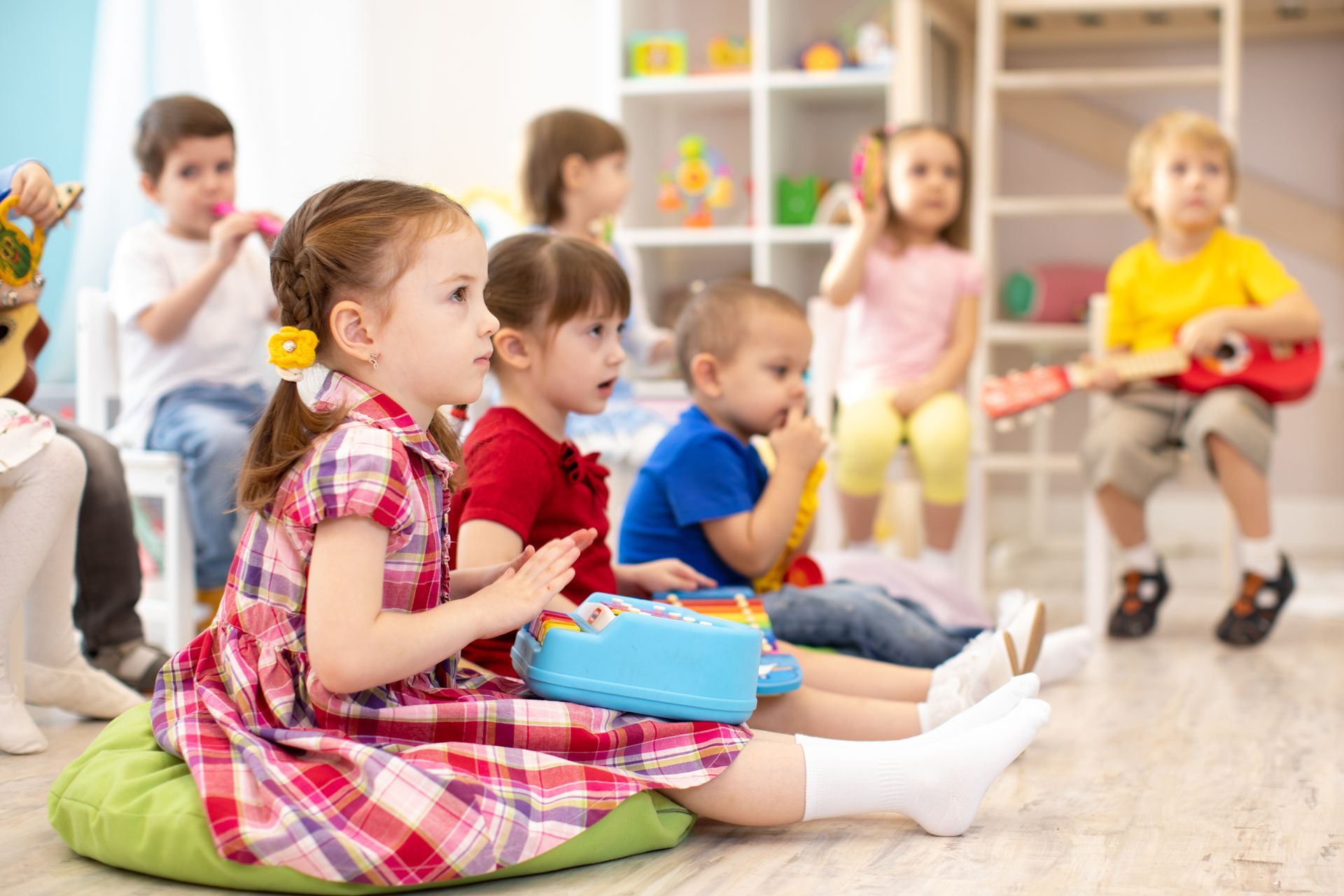 Children sitting in a classroom circle, holding toys and books during group time