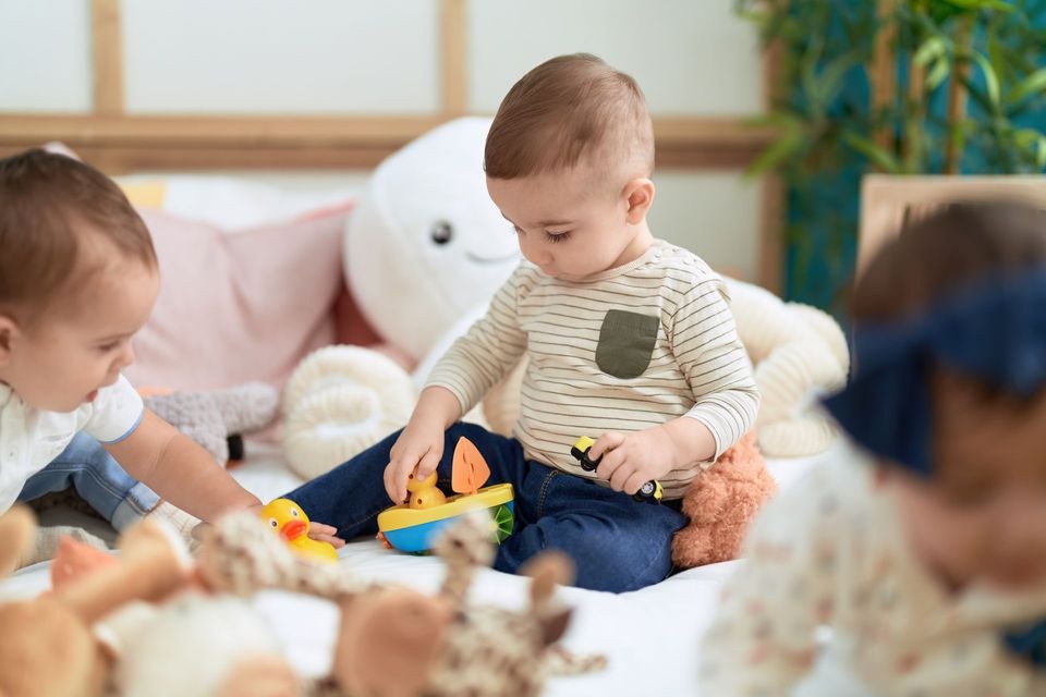 Children playing with toys on a soft play mat in a bright room