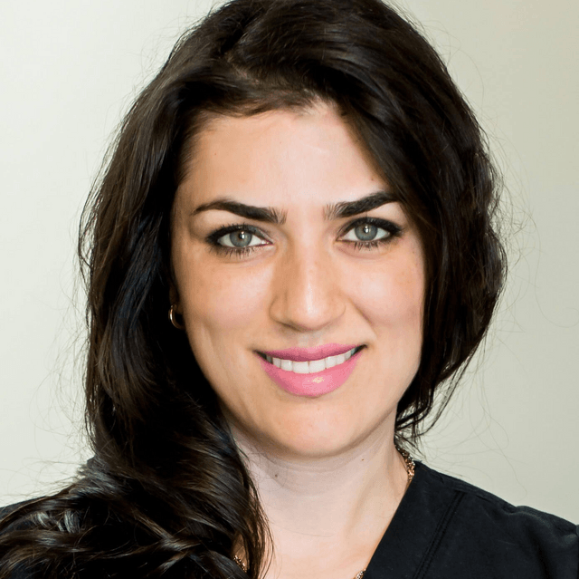 A woman with long dark hair is smiling for the camera