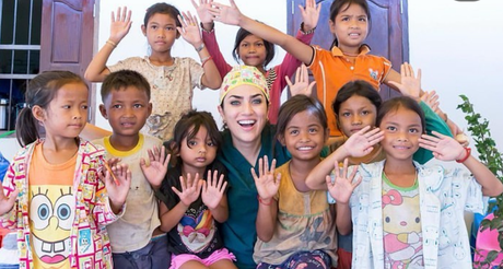 A woman is posing for a picture with a group of children.