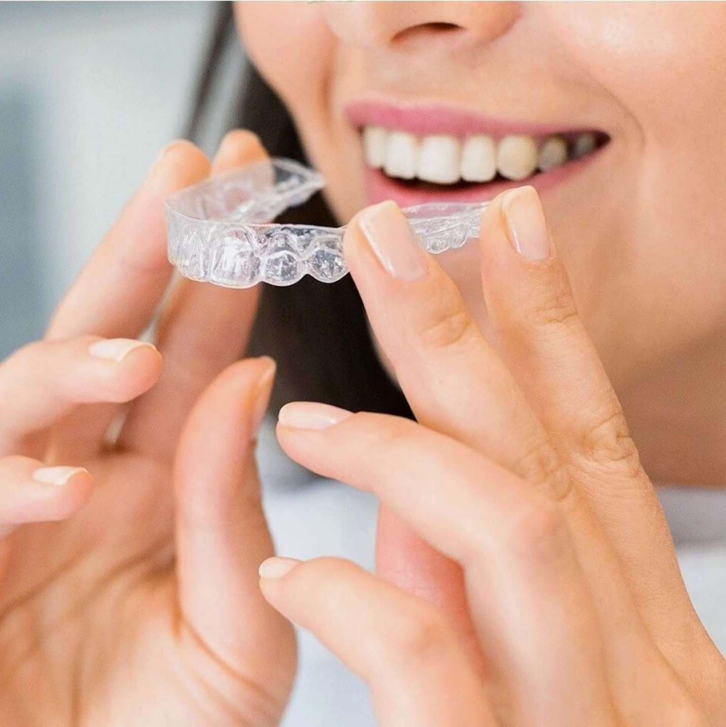 A woman is holding a clear brace in her hands.