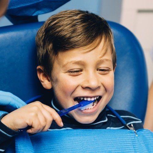 A young boy is brushing his teeth with a blue toothbrush