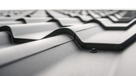 Close-up of a dark gray metal roof with overlapping panels and curved edges.
