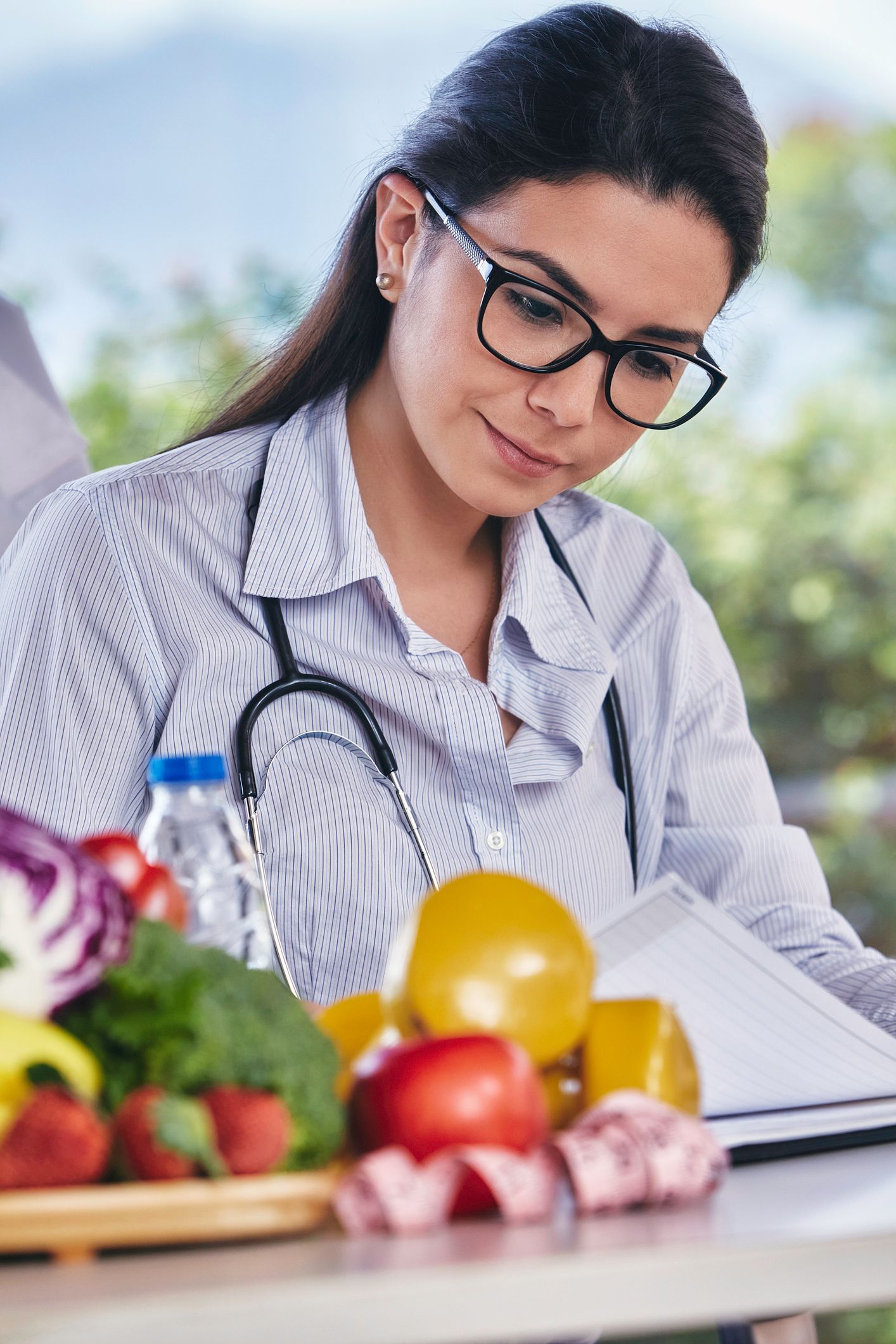 A doctor is talking to a patient while holding an apple.