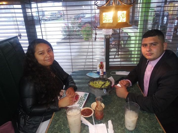 Couple seated at a restaurant table, guacamole and drinks in front of them, looking at the camera.