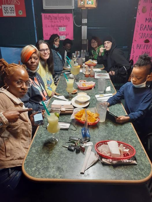 Group of people at a table in a restaurant. They are drinking cocktails and smiling.
