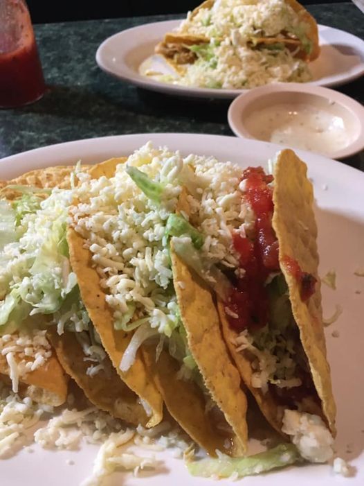 Hard shell tacos with shredded lettuce, cheese, and salsa.