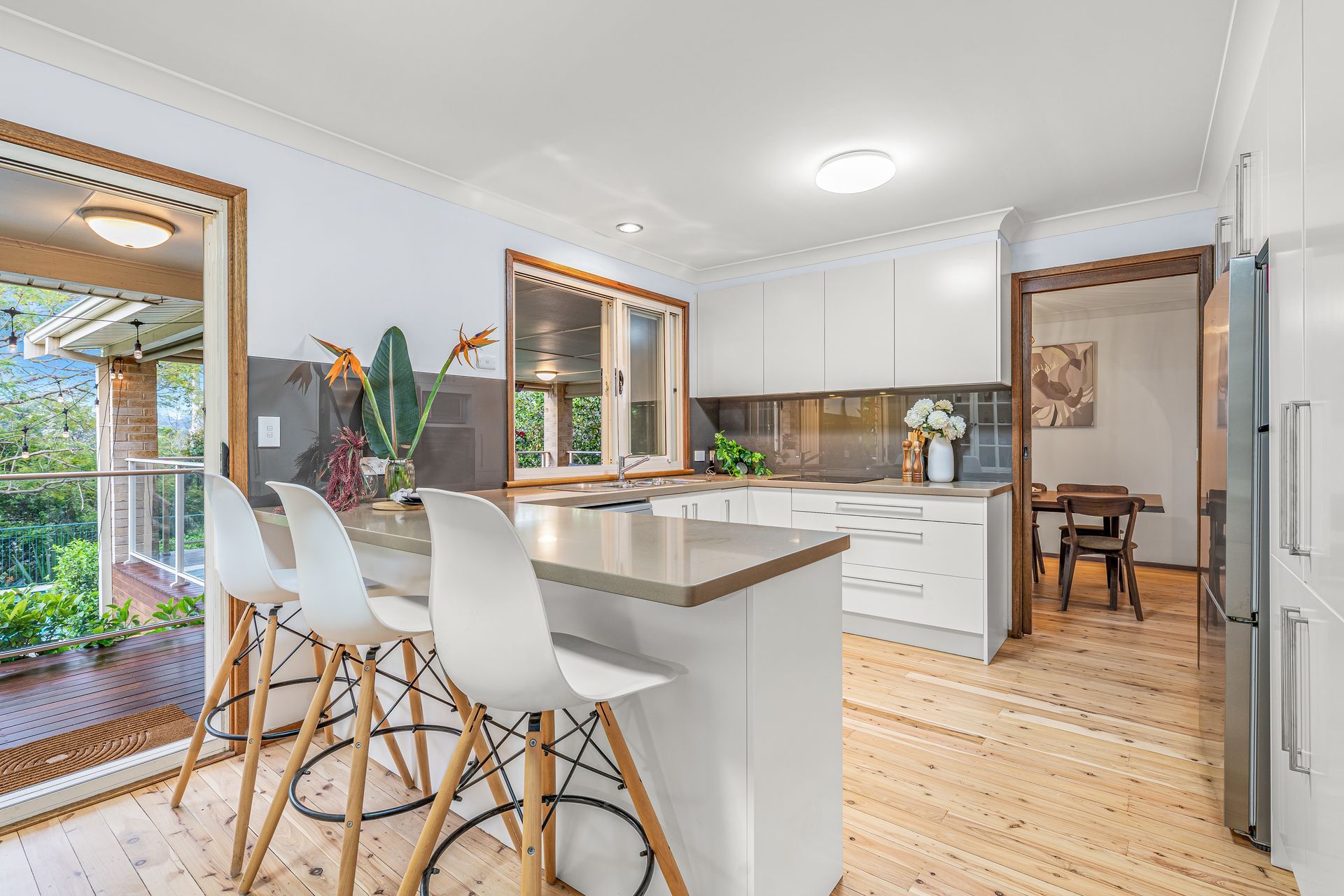 A Bright Kitchen With White Cabinets, a Light Wood Floor, a Stone Island — Brightside Buyers Agency in Dundas, NSW