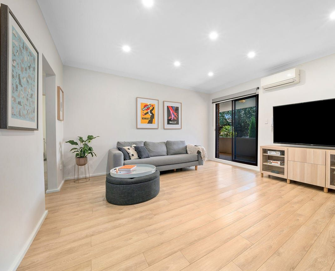 A Bright Living Room With Light Wood Floors, a Grey Sofa, Matching Ottoman — Brightside Buyers Agency in Dundas, NSW