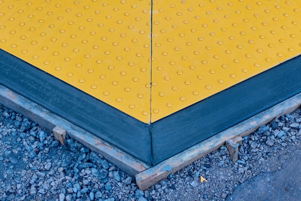 A yellow tile with a blue border is sitting on top of a pile of gravel.