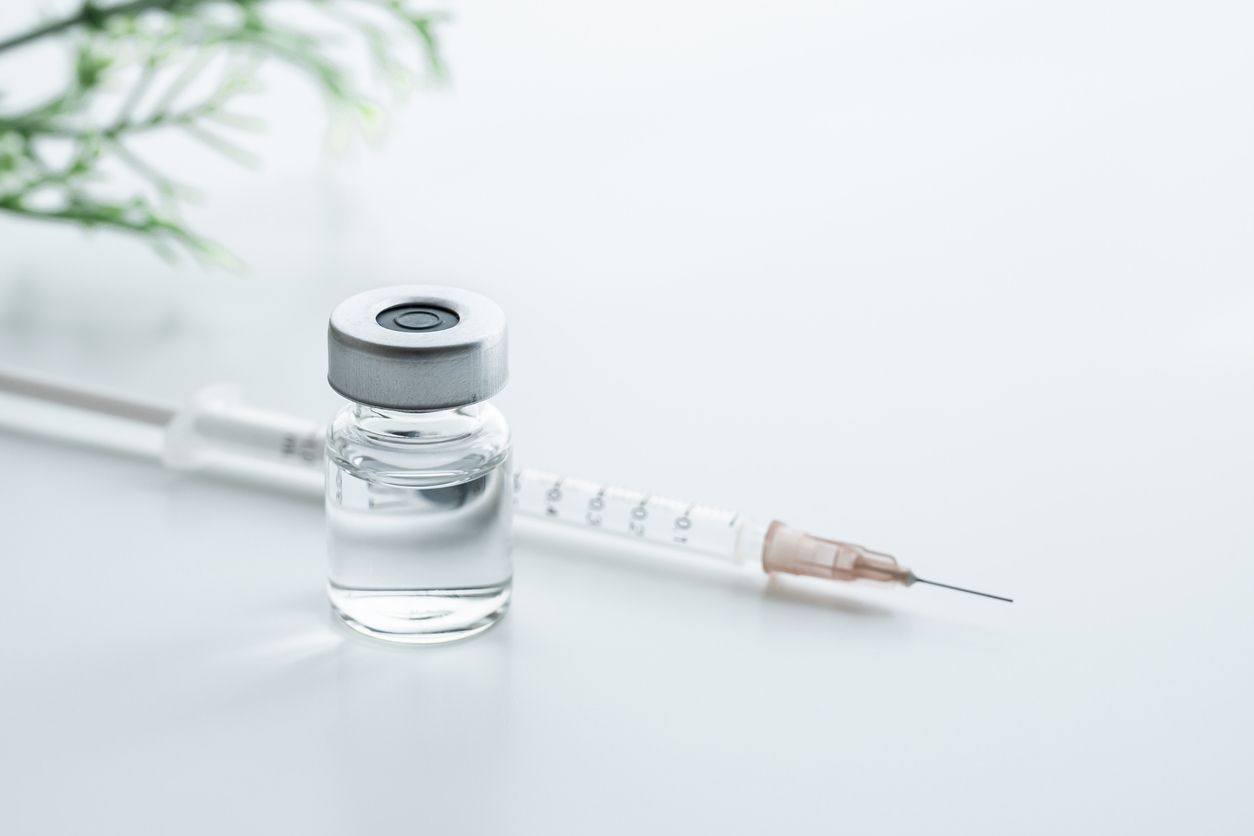 A bottle of liquid and a syringe on a table.