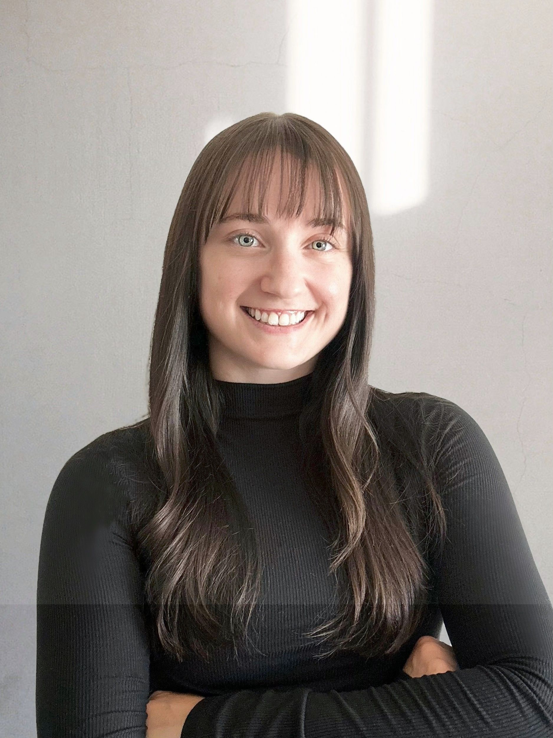 Jess, the owner of Turn Right Services, LLC, smiling against a plain light wall