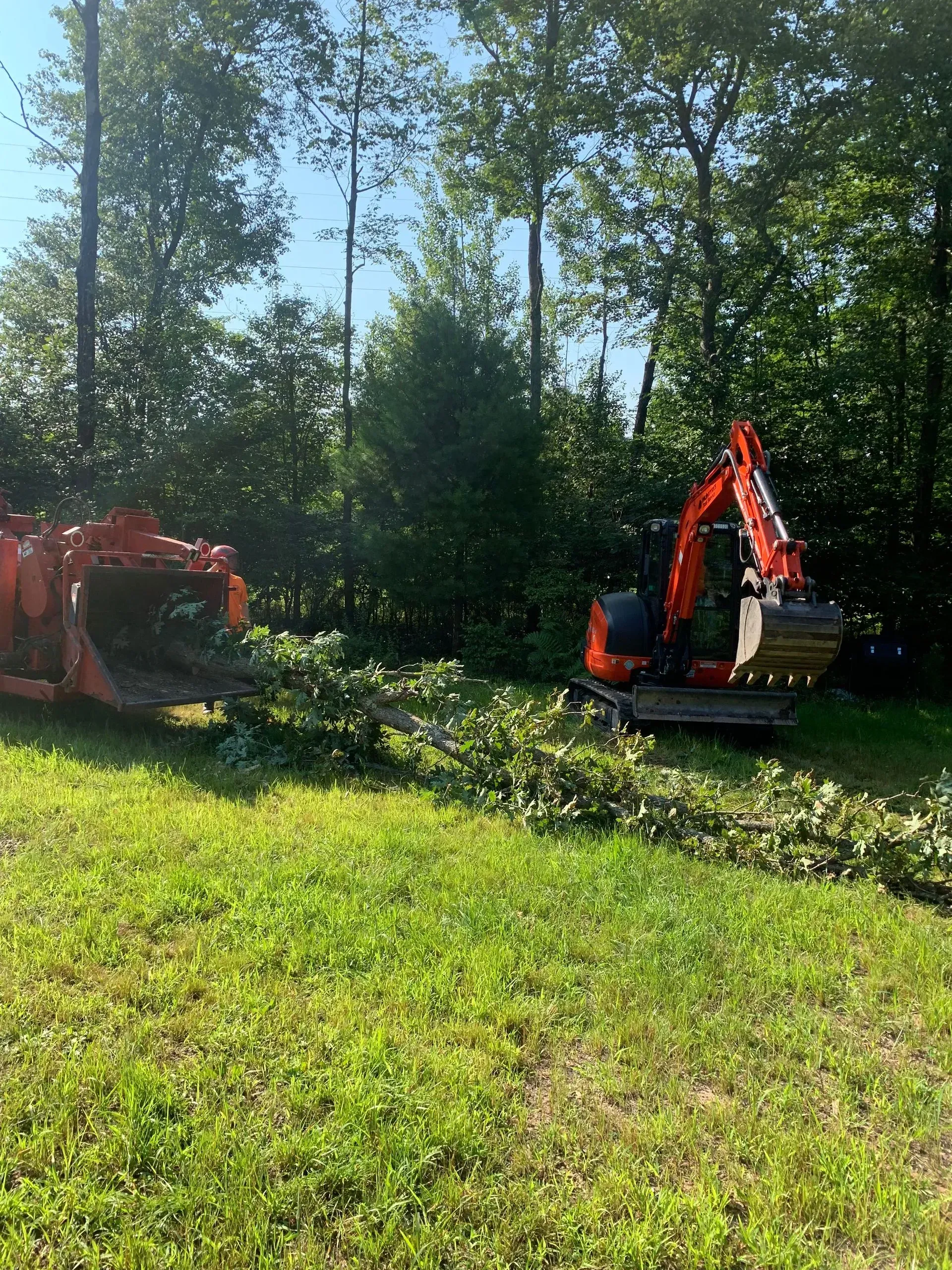 A red excavator is sitting on top of a lush green field.