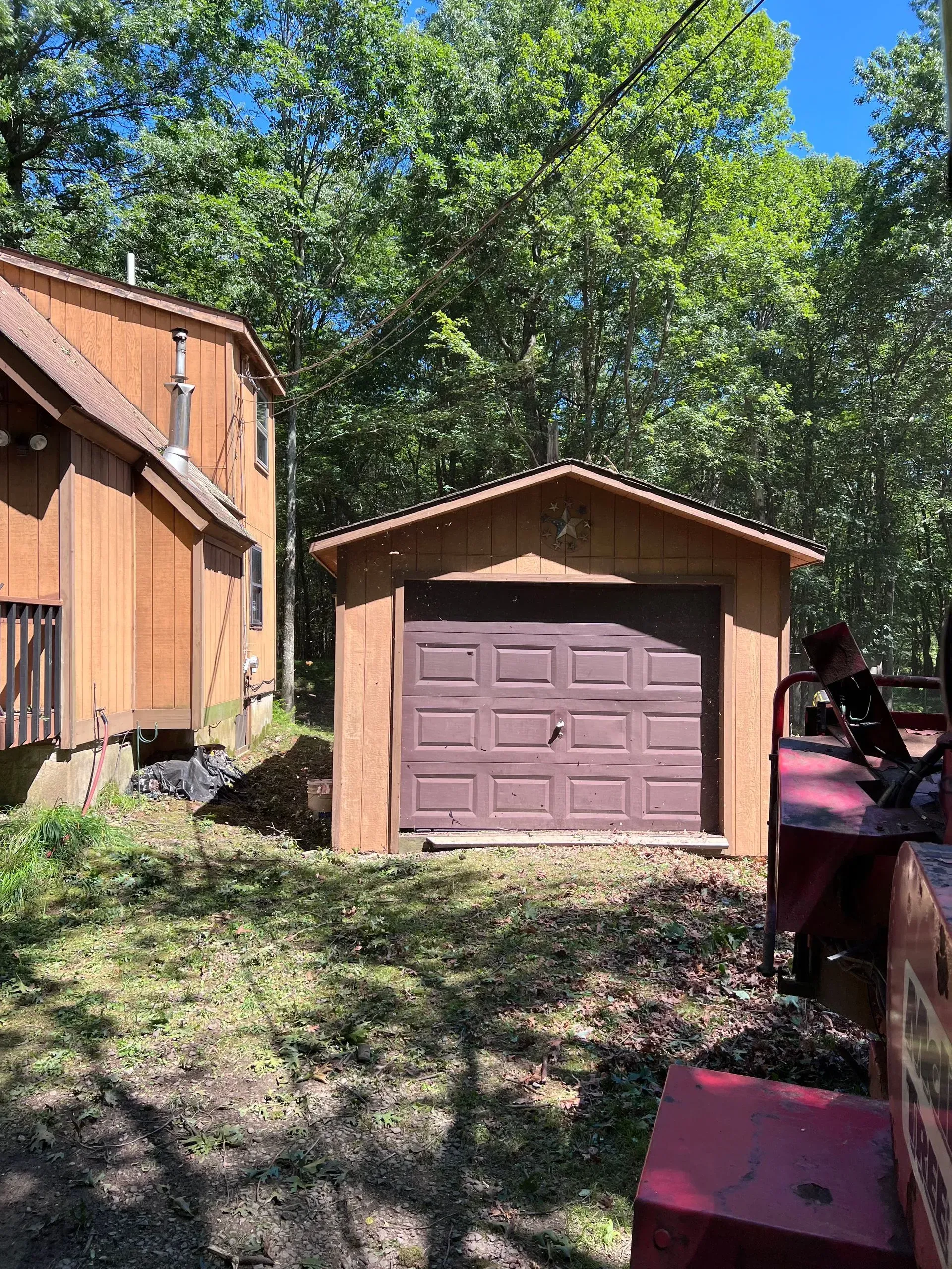 A garage with a brown door is in the backyard of a house.
