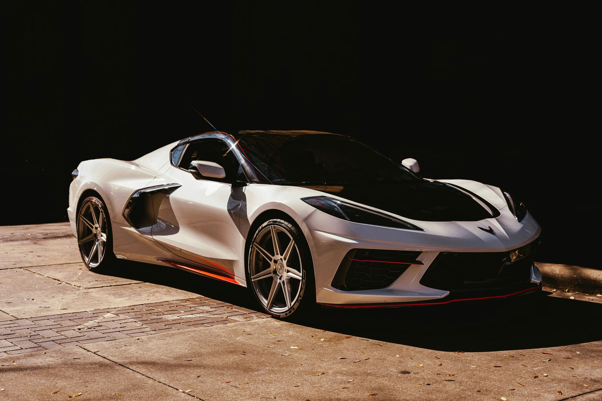 White and black sports car parked on a sunny pavement.