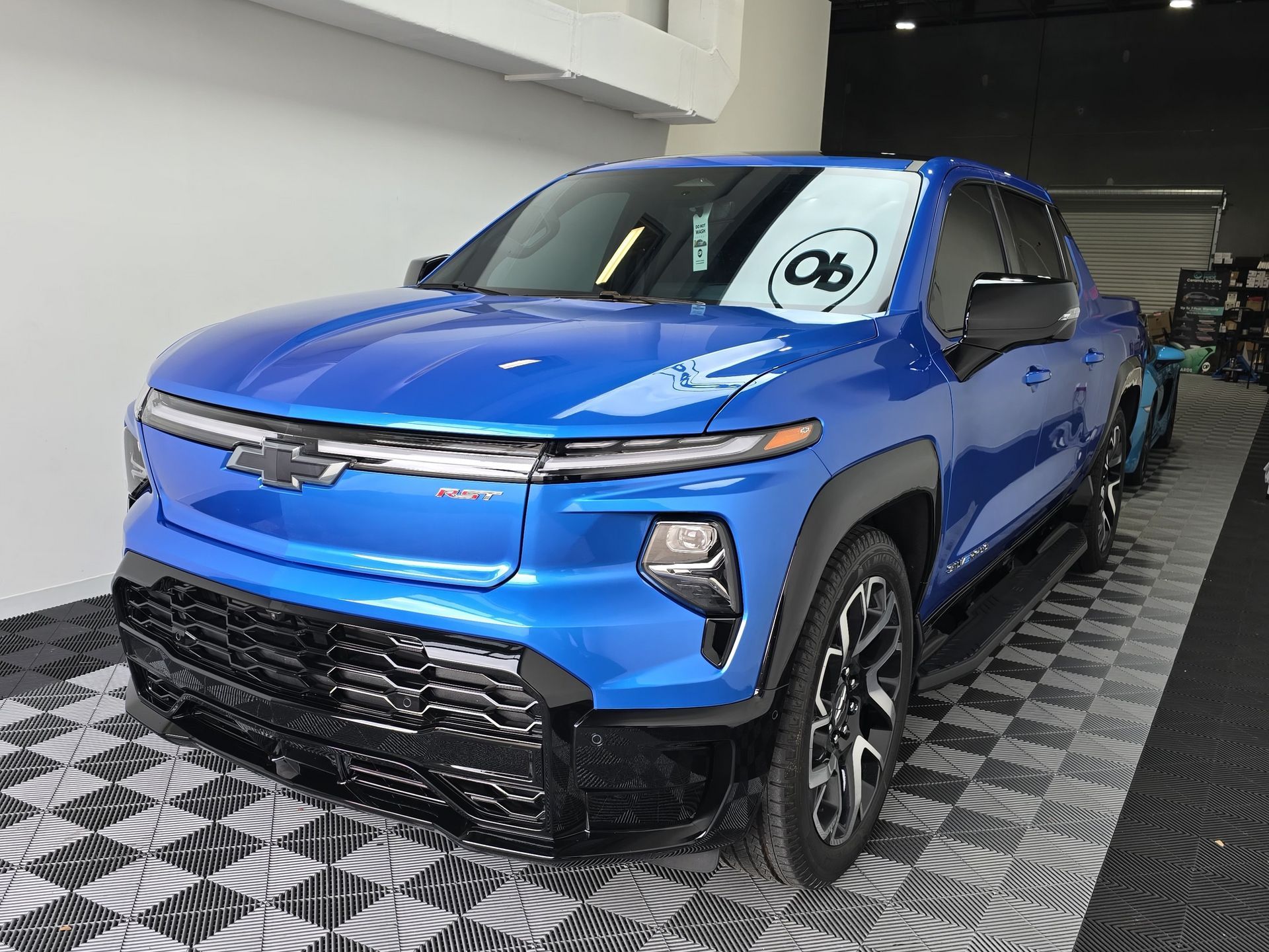 A blue truck is parked on a checkered floor in a showroom.