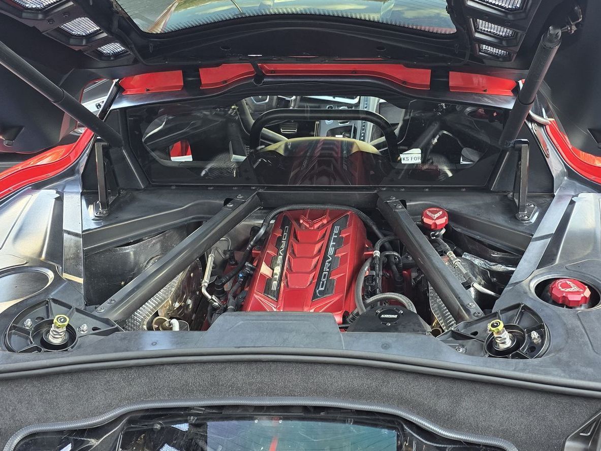The engine of a sports car is shown with the hood open.