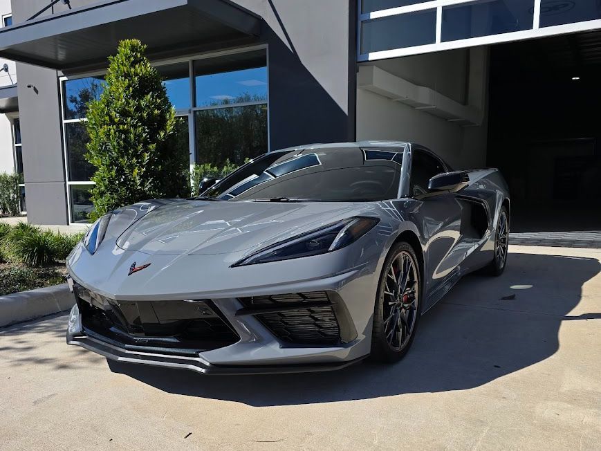 A gray Corvette is parked in front of a building.