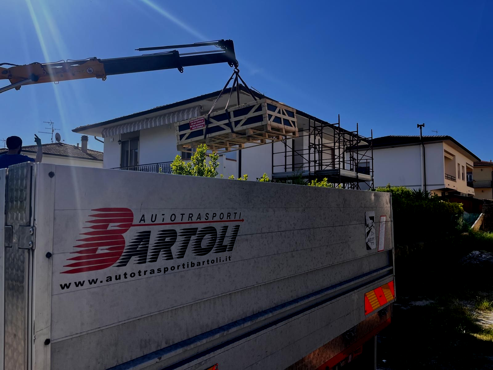 Tre camion Iveco parcheggiati in un piazzale, uno bianco e uno grigio, con alberi e cielo sullo sfondo.