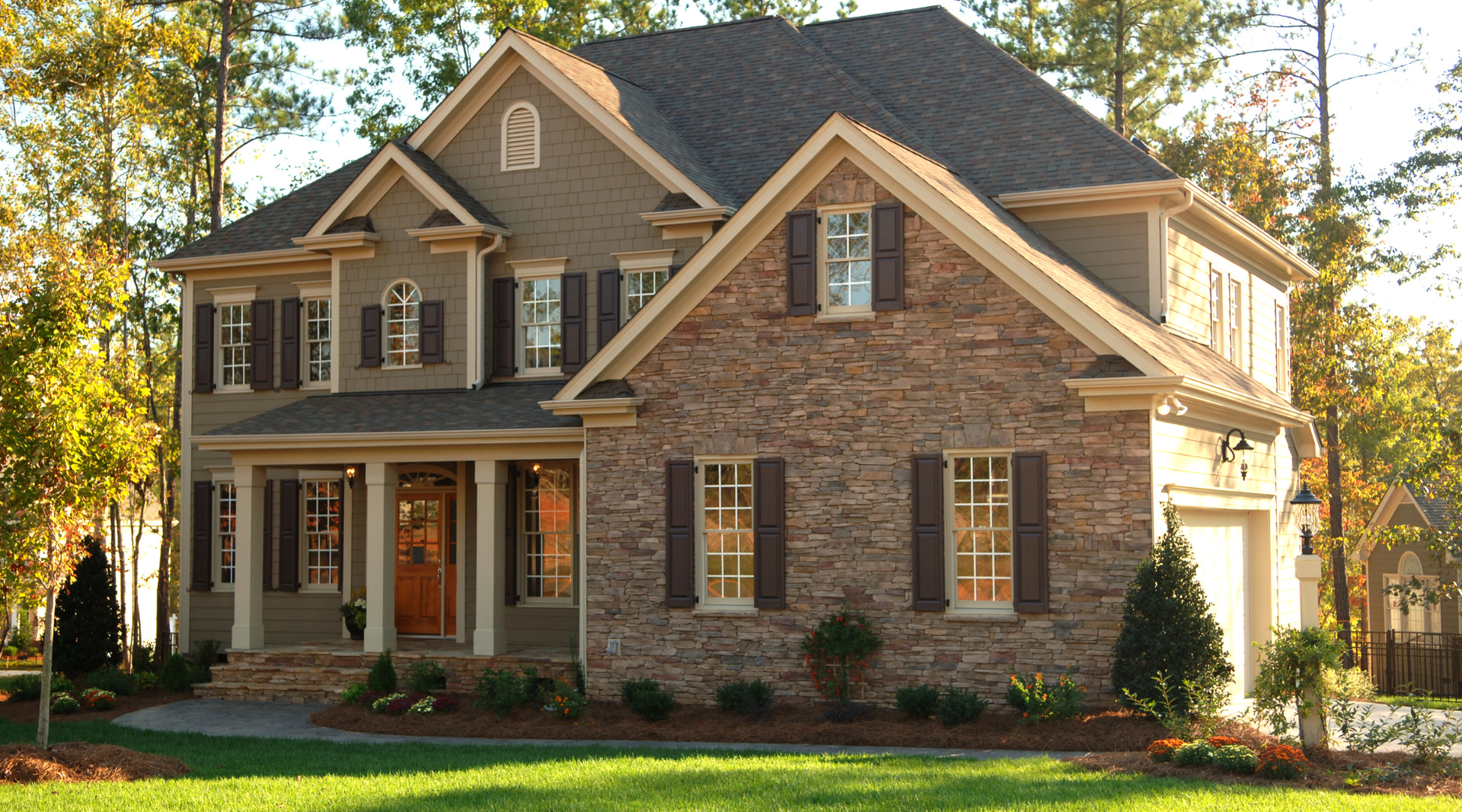 A large house with a blue roof is sitting on top of a lush green hillside.