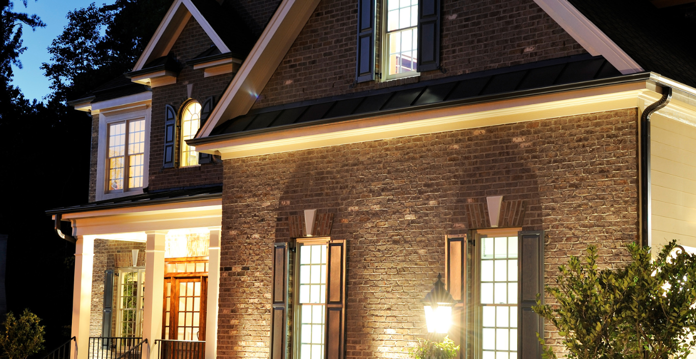 A large brick house with lots of windows is lit up at night.