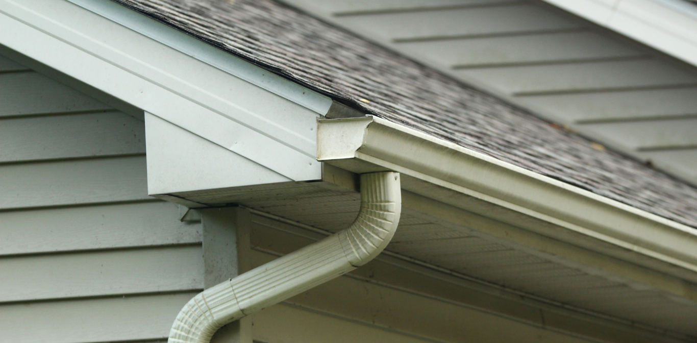 A close up of a gutter on the side of a house.