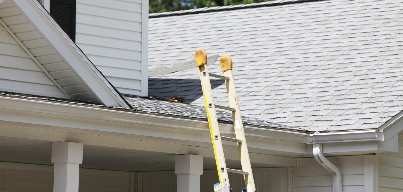 A ladder is sitting on the roof of a house.