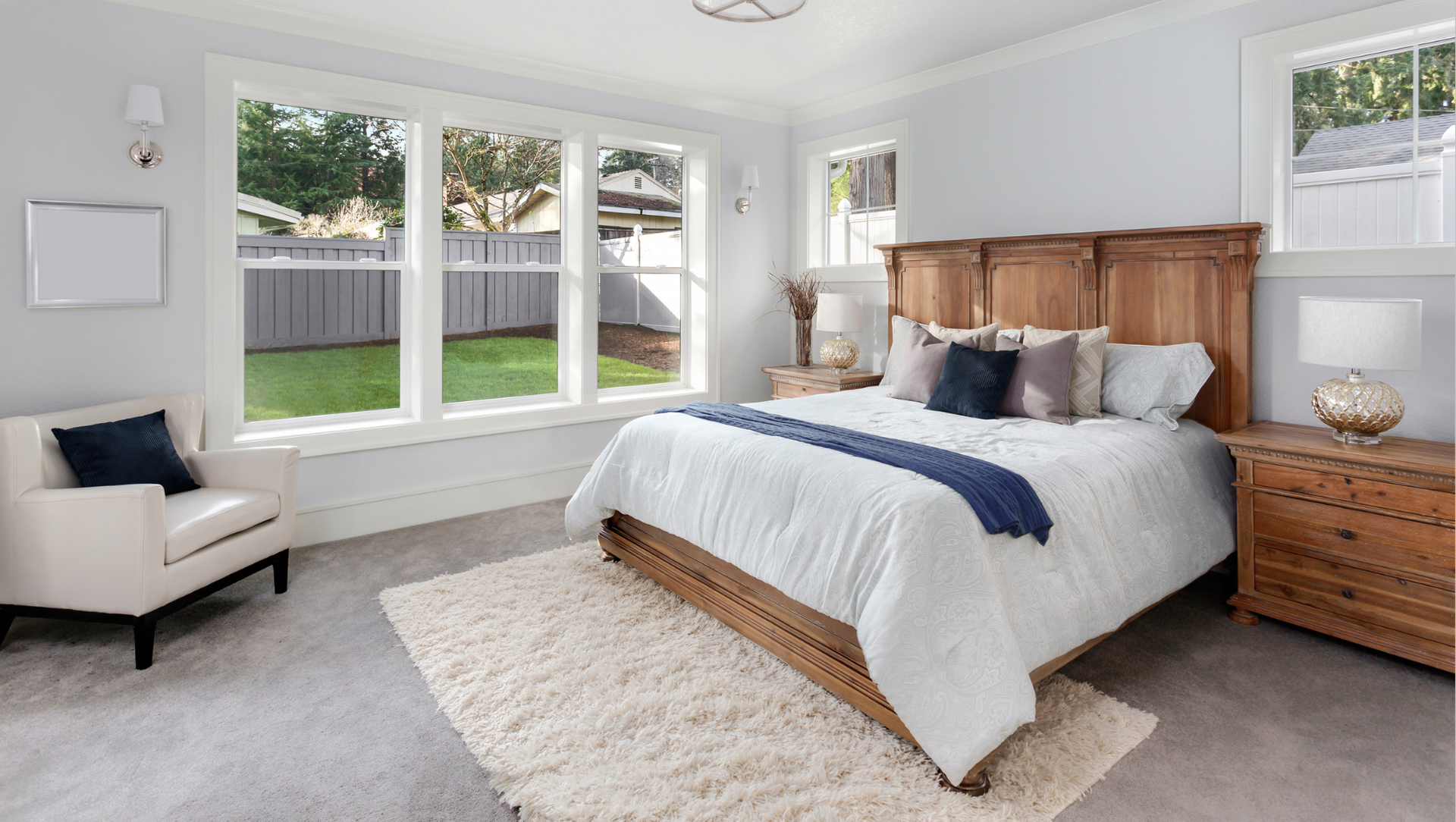 A bedroom with a bed , chair , nightstand , dresser and windows.