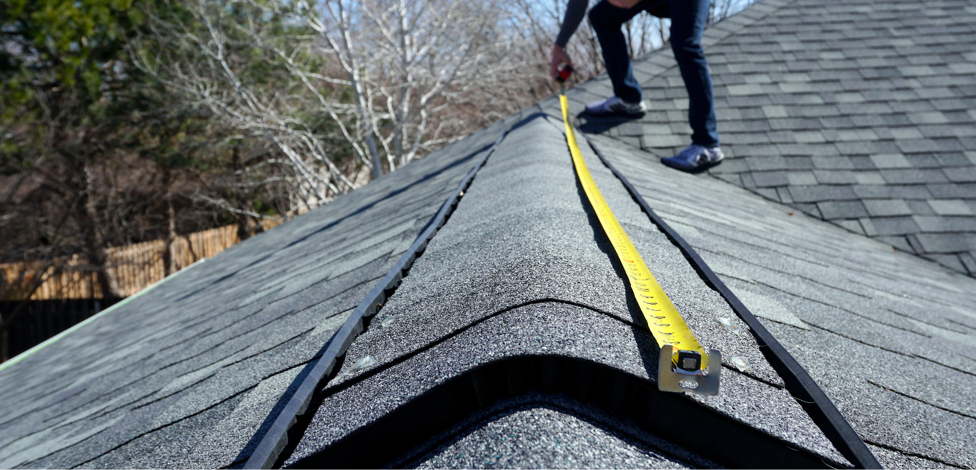 A man is measuring a roof with a tape measure.