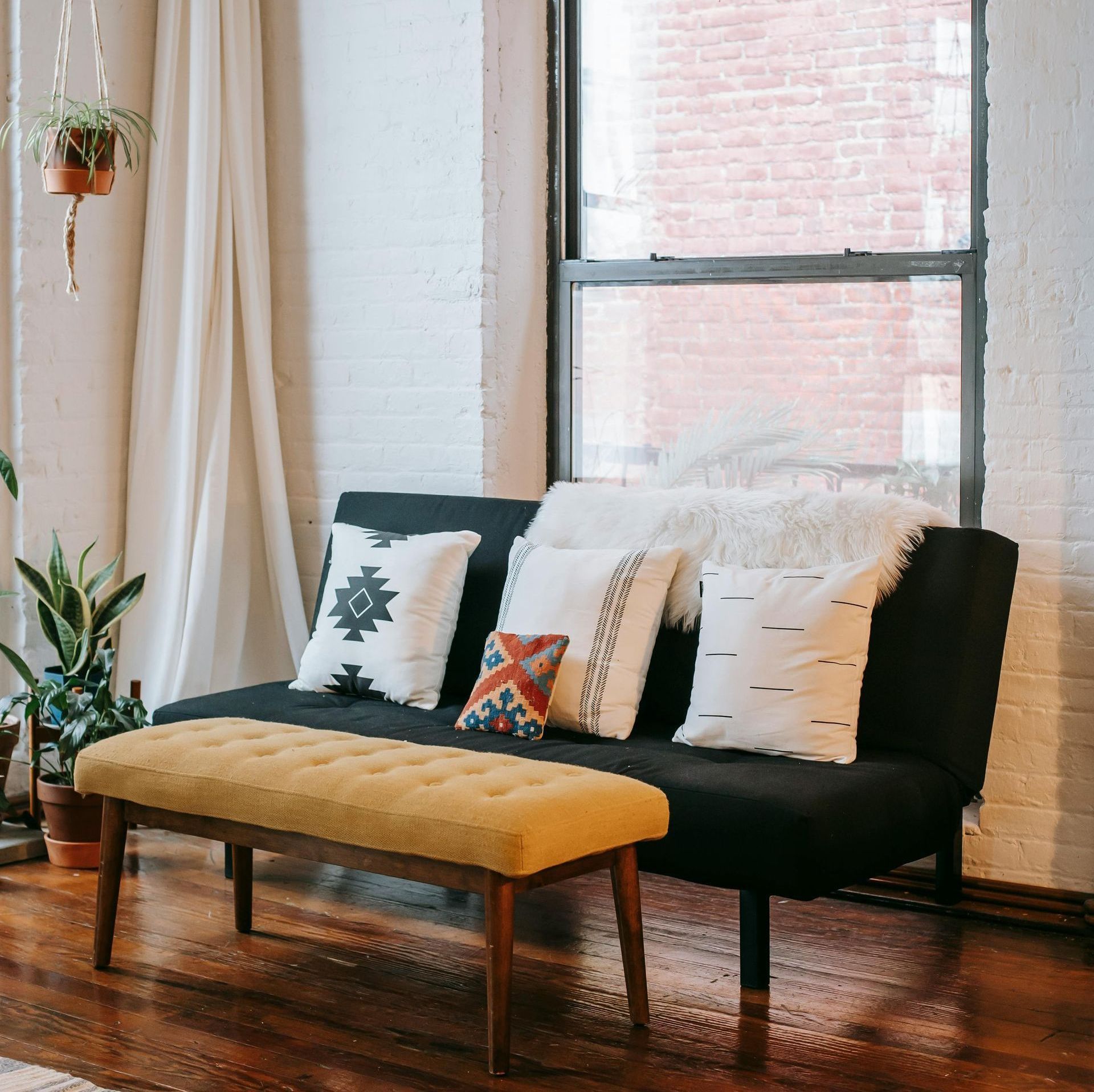 A living room with a black couch and a yellow bench