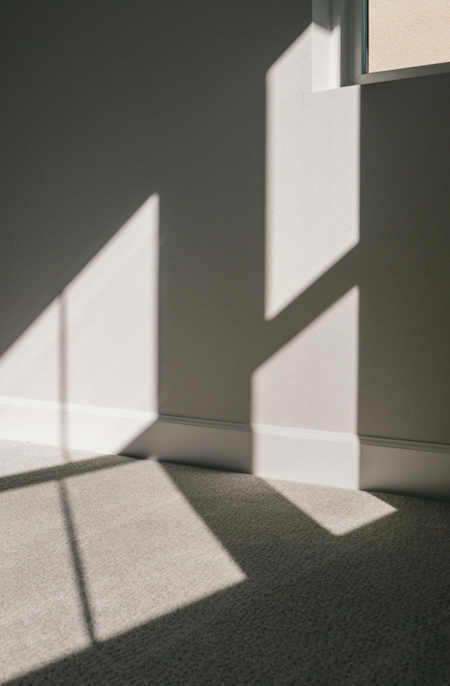 The sun is shining through the window and casting a shadow on the floor.