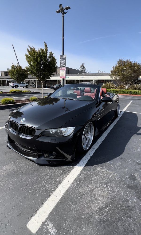 A black bmw convertible is parked in a parking lot.