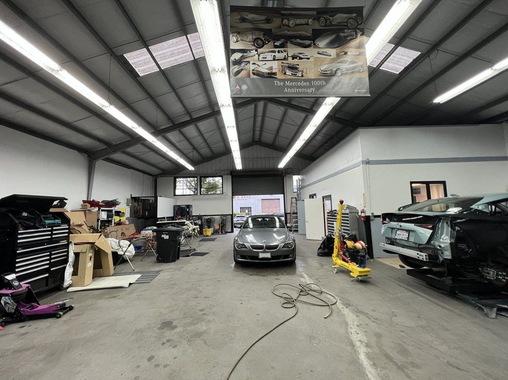 A car is parked in a garage with a sign hanging from the ceiling.