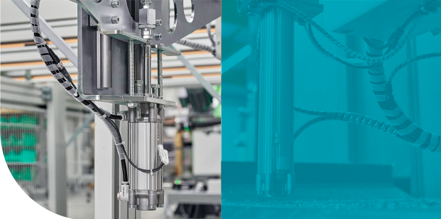 Máquinas industriais em uma fábrica, parcialmente sobrepostas por um painel gráfico verde-azulado.